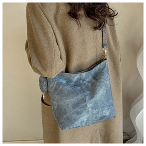 Détail du cabas vintage bleu avec bandoulière bohème large porté sur un manteau marron
