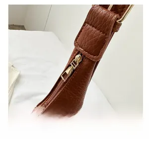 Close-up of smooth gold zipper and hardware on a brown lychee pattern tote bag