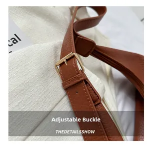 Detail of adjustable shoulder strap with gold buckle on brown pebble leather tote bag