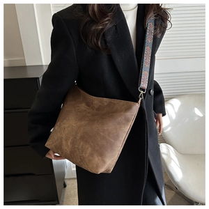 Detail of vintage brown suede tote with ethnic patterned woven strap and gold hardware