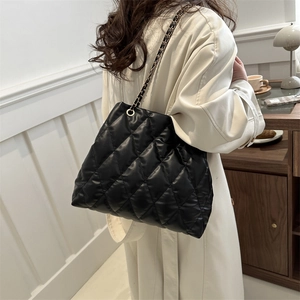 Chic quilted black chain tote bag displayed as a crossbody on a stylish trench coat
