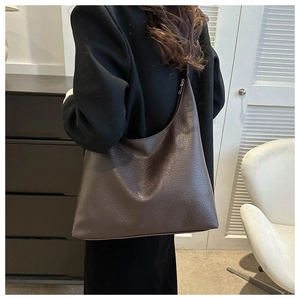 Brown large capacity tote bag with lychee leather texture worn by a model in interior setting
