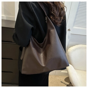 Detail of dark brown lychee grain leather tote bag worn with a black blazer