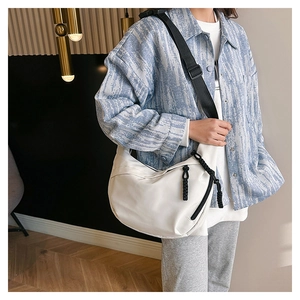 White crescent crossbody bag with black adjustable strap and woven zipper pull detail
