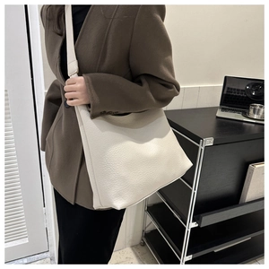 Chic beige faux leather tote bag with pebble texture shown on a model in a stylish setting