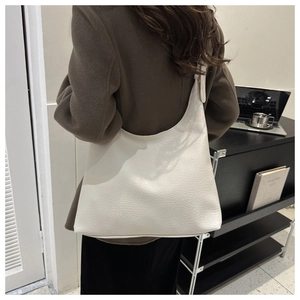 Close-up of a beige lychee pattern leather tote bag on a female model for daily commute