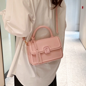 Pink minimalist crossbody square bag with top handle and fashion tag shown on a model