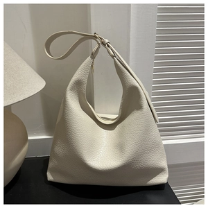 Detail of cream hobo bag showing pebble grain leather and golden metal hardware