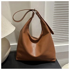 Detail of caramel brown large capacity hobo bag featuring textured lychee grain leather
