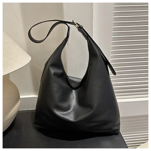 Detail of black pebbled leather texture on tote bag with golden metal strap buckle
