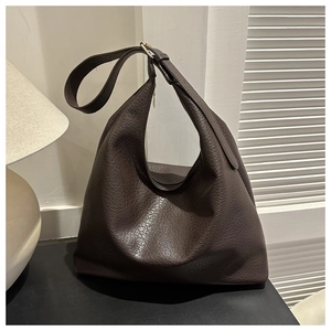 Detail of dark brown lychee pattern leather texture and gold hardware on tote bag