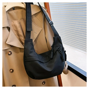 Detail of black nylon crescent bag with woven zipper puller and wide adjustable strap