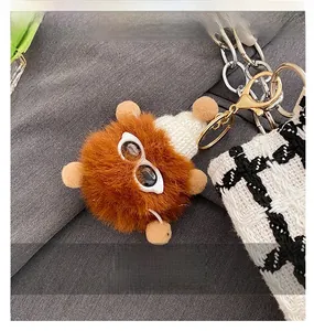 Close-up of a plush bear charm with sunglasses on a woven tote bag strap