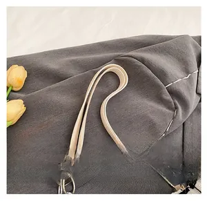 Detail of the cream leather shoulder strap with silver metal rings and thick chain link