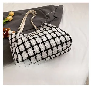 Detail view of the black and white tweed woven tote bag bottom and reinforced corner stitching