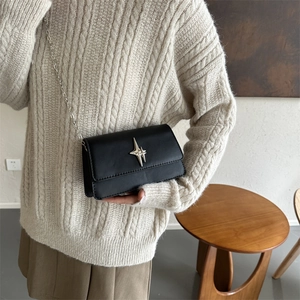 Minimalist black square crossbody bag with a silver star buckle and fine chain strap