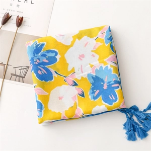 Detailed close-up of yellow floral scarf featuring elegant blue tassels and cotton fabric