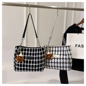 Close-up of woven checkered tote bags with chain straps and plush monster charms