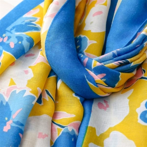 Detailed macro view of yellow and blue floral cotton scarf with soft woven texture