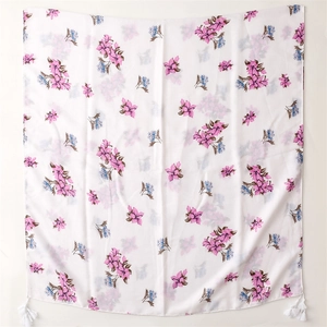 Detail of floral linen scarf with pink petals, blue flowers, and white tassels