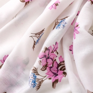 Close-up of white cotton-linen scarf fabric with pink floral prints and fringe edges