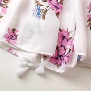 Close-up of cotton linen scarf with pink floral pattern and white cotton tassels