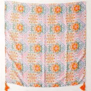 Detail of ethnic scarf showing geometric floral prints with orange tassels on soft fabric