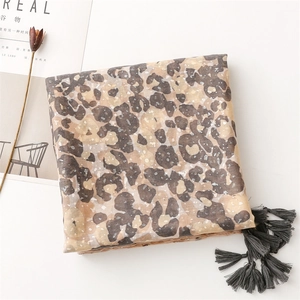 Detailed view of leopard print scarf featuring silver foil accents and grey fringe tassels