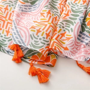 Close-up of geometric pattern on cotton linen scarf with bright orange tassel details