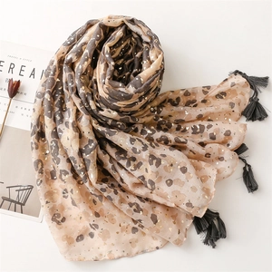 Lightweight leopard print shawl with gold foil accents and fringe, shown with magazine