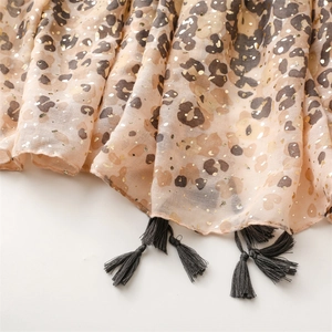 Close-up of lightweight leopard print scarf with gold foil dots and dark grey tassels