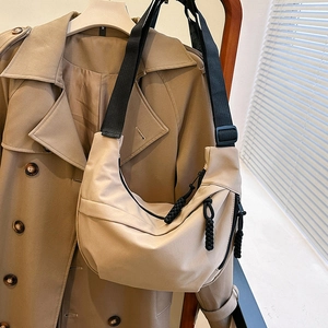 Minimalist beige half-moon crossbody bag with black adjustable strap and woven zipper pull
