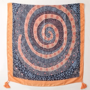 Detail of bohemian scarf with ethnic spiral patterns, orange hem, and corner tassels