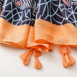 Detailed close-up of geometric pattern scarf with bright orange tassel trim detail