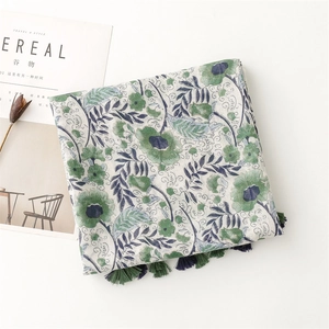 Detailed view of floral cotton shawl featuring blue-green blossoms and navy tassels