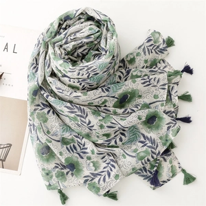 Detail of floral printed scarf with blue and green tassels on cotton linen texture