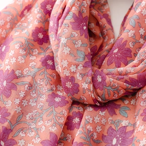 Detailed texture of floral scarf with vibrant orange base and soft purple flower patterns