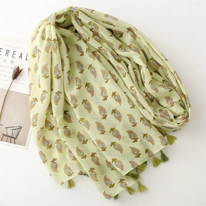 Light green cotton linen scarf with leaf prints and fringes, styled with magazines