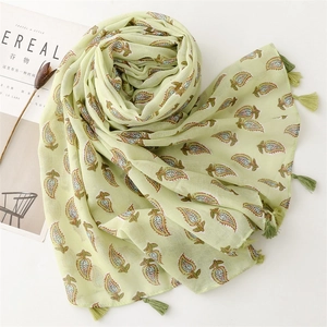 Detail of light green scarf with leaf print and tassel fringe on white background