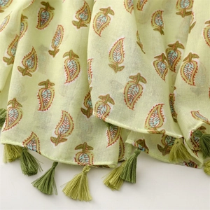 Close-up of light green paisley beach scarf with cotton-linen texture and green fringe tassels