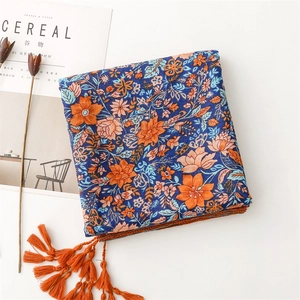 Detail of bohemian scarf with vibrant floral print and long orange tassels on edges