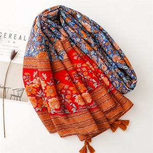 Ethnic style floral shawl with red and blue tones and orange tassels on white background