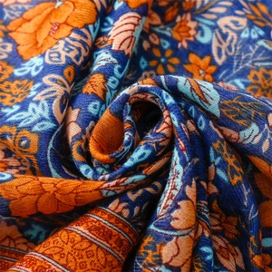 Macro detail of Bohemian cotton linen shawl with blue and orange ethnic floral patterns