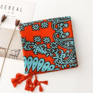 Detailed view of orange paisley shawl with tassels and blue floral patterns