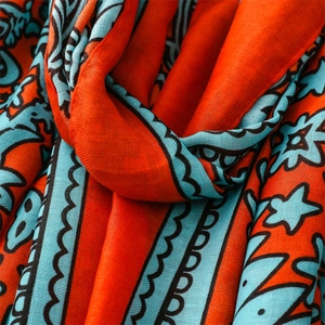 Detail of cotton-linen feel scarf with vintage ethnic prints in orange and teal colors