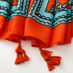 Detail of bohemian ethnic shawl with orange tassels and turquoise floral patterns