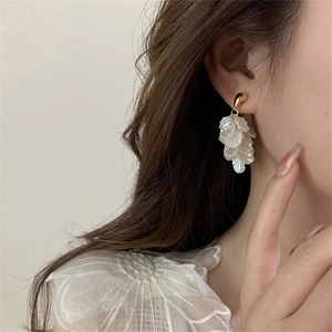 Detail of petal tassel earrings with creamy white shell texture and gold metal accents