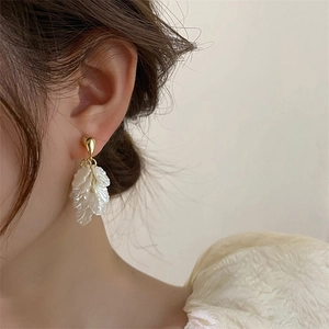 Detail of elegant white layered flower petal tassel earrings with golden metallic studs