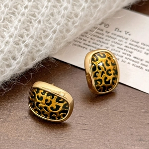 Boucles d'oreilles léopard vintage avec cadre doré sur fond en bois naturel