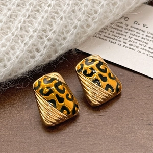 Macro view of geometric leopard print enamel earrings with gold-plated ribbed metal finish